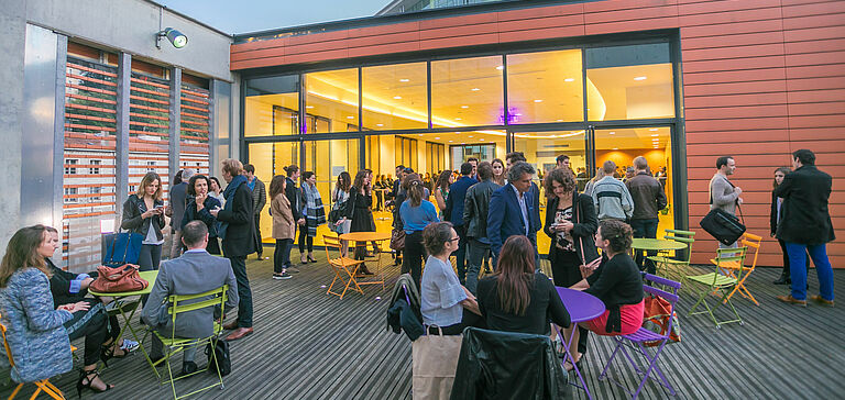 Groupe de personnes rassemblées sur une terrasse extérieure