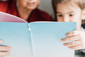 Une personne âgée lit un livre avec un enfant