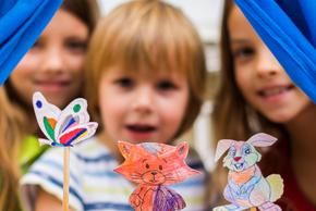 Des enfants tendent des marionnettes faites en papier.