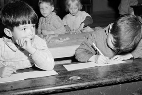 Des écoliers font leurs devoirs sur les bancs de l'école dans les années 50.