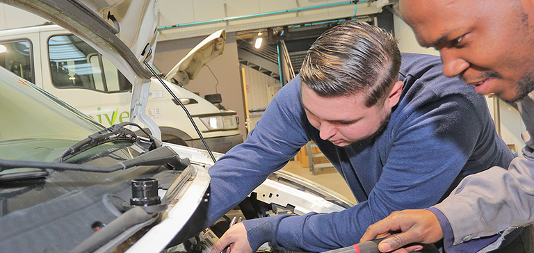 Deux personnes travaillant sur la réparation d'un véhicule