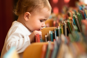 Un bébé regarde dans les rayonnages d'une bibliothèque