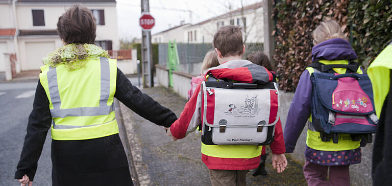 Enfants allant à l'école en compagnie d'une accompagnatrice