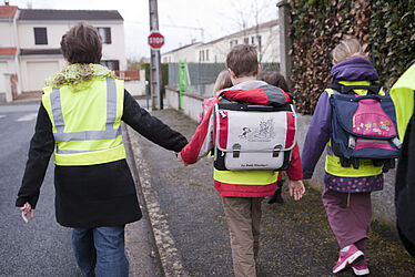 Enfants allant à l'école en compagnie d'une accompagnatrice
