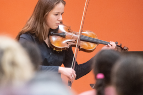 Une personne joue du violon devant un public.