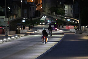 Deux cyclistes circulent sur un pont de nuit à Poitiers.