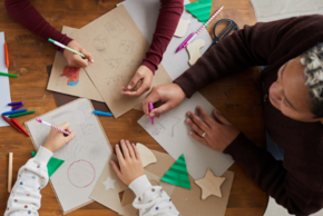 Des enfants sont en train de dessiner des ornements de sapins de Noël.