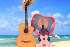 Deux guitares sont posées sur le sable. Elles ont des chapeaux.