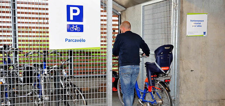 Homme déposant son vélo dans un Parcavélo