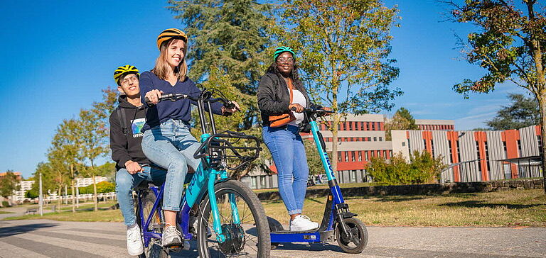 Personnes sur un vélo et une trottinette en libre-service