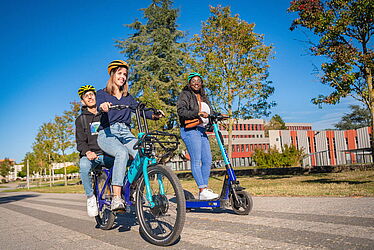 Personnes sur un vélo et une trottinette en libre-service