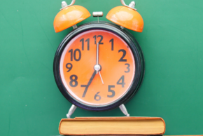 Image d'illustration : un réveil vintage est posé sur une pile de livres.