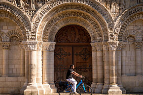 Photo d'un cycliste passant devant Notre-Dame-la-Grande