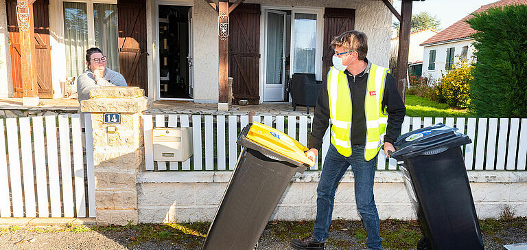 Professionnel distribuant deux bacs à une femme, devant chez elle